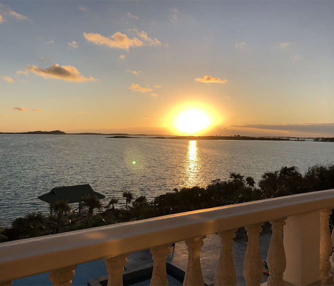 View off a balcony with a sunset over the ocean